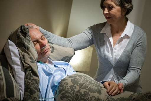 Sick lying senior man with caring wife at home