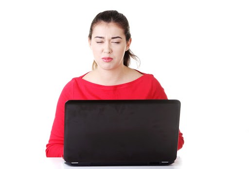 Surprised and disgusted woman working on laptop