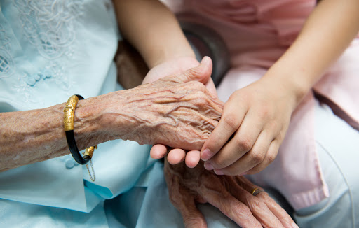 Young girl&#8217;s hand touches and holds an old woman&#8217;s wrinkled &#8211; it