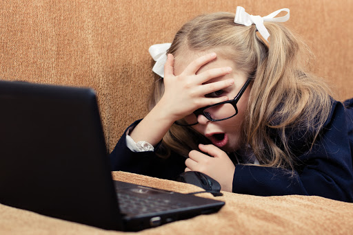 Cute schoolgirl with glasses and laptop in a state of shock &#8211; it
