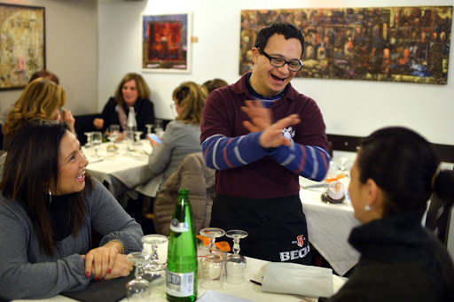 a young man with Down syndrome, jokes with clients as he works in the restaurant &#8220;Locanda dei Sunflowers&#8221; &#8211; it