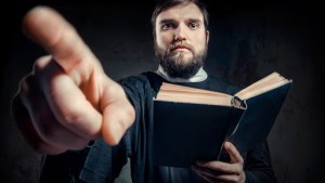 Priest with Prayer book against dark background – it