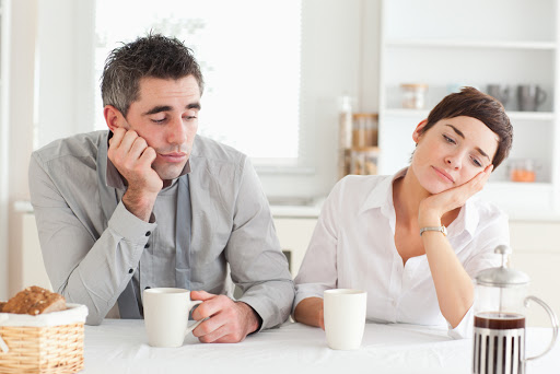 Exhausted couple drinking coffee in a kitchen