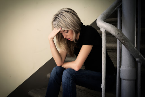 Young unhappy woman in depression sitting on stairs