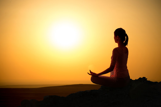 Girl practicing yoga at sunrise