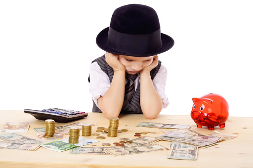 Sad boy in black hat at the table with pile of money - it
