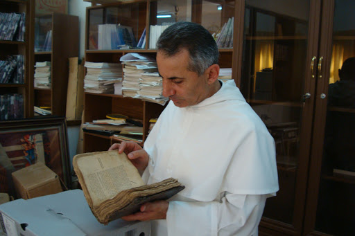 Father Najeeb Michaeel examines a manuscript &#8211; it