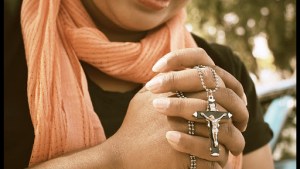 Woman hands praying with cross © successo images / Shutterstock – it