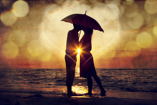 Couple kissing under umbrella at the beach in sunset © Masson / Shutterstock
