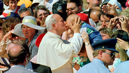 Pope John Paul II kisses a baby as he is welcomed to Australia in 1986. &#8211; it