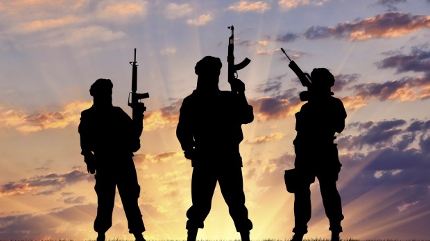 Concept of a terrorist. Silhouette terrorists with rifle at sunset