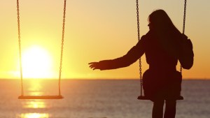 single-woman-swinging-beach-sunset