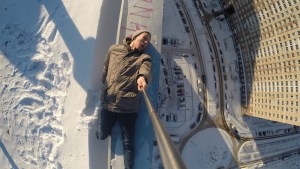 man selfie on edge of roof of tall building