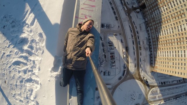 man selfie on edge of roof of tall building