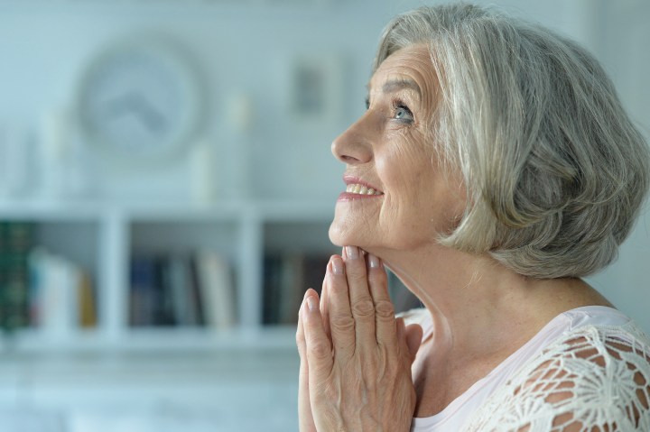 ELDERLY WOMAN PRAYS,