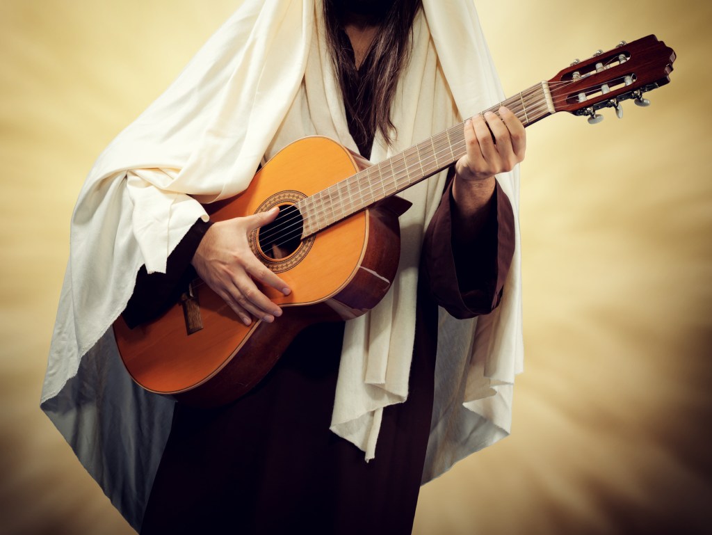Man wearing Jesus Christ costume and plays guitar