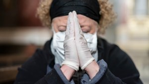 Senior-woman-in-gloves-and-mask-praying-in-a-church