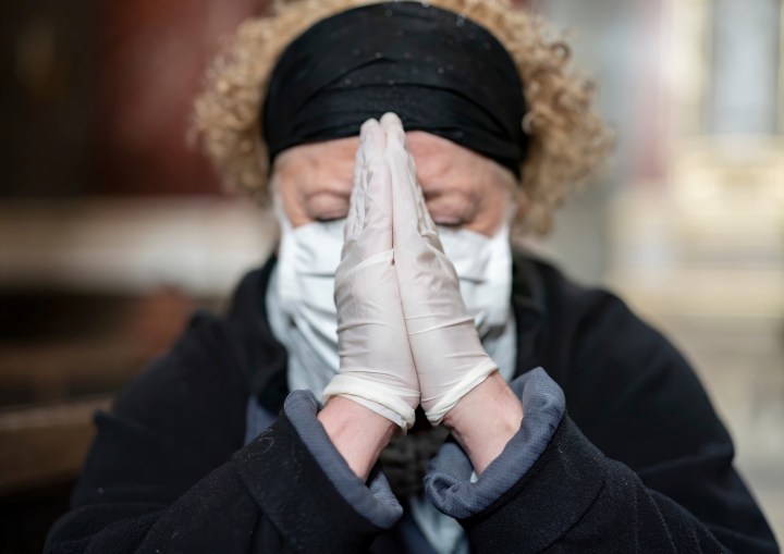 Senior-woman-in-gloves-and-mask-praying-in-a-church
