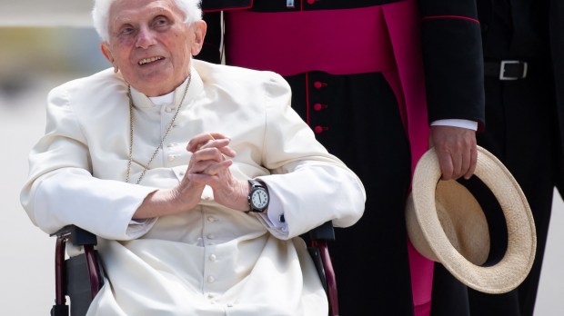 Nella foto Benedetto XVI sulla sedia a rotelle con le mani giunte