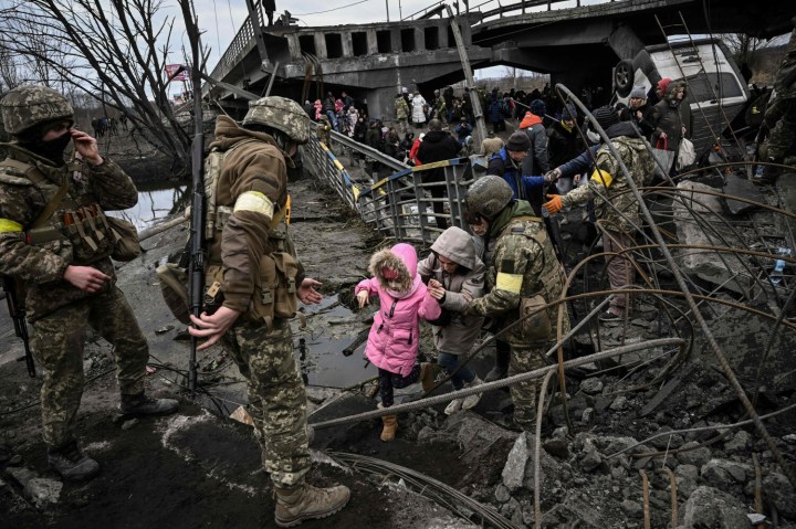 Uciekający przed wojną mieszkańcy Irpienia przedostają się przez zniczony most