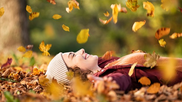 Woman-lying-over-autumn-ground-relaxing-at-park-shutterstock