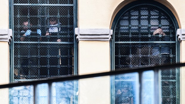 Inmates-hang-on-to-bars-behind-windows-of-a-wing-as-they-stage-a-protest-at-the-San-Vittore-prison-in-Milan-AFP