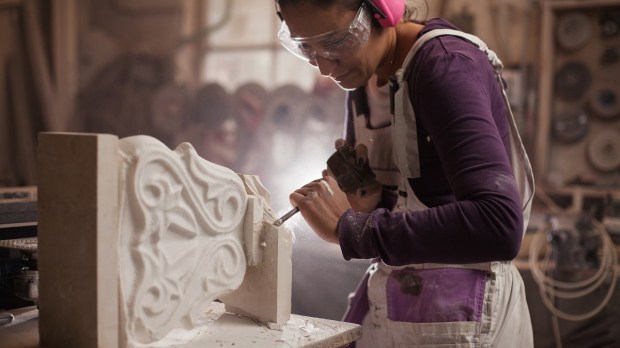 Female sculptor working on a piece using hammer and chisel.
