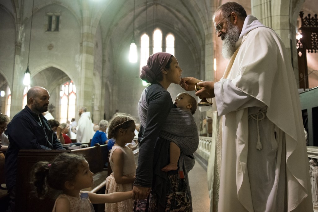 young mom and little children in church receiving eucharist